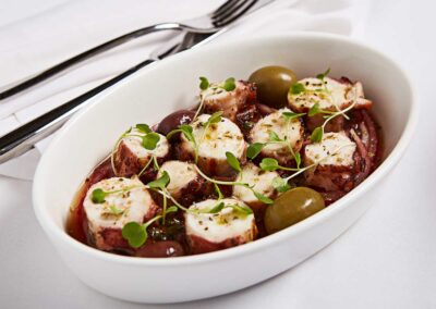 grilled calamari with olives in a white dish